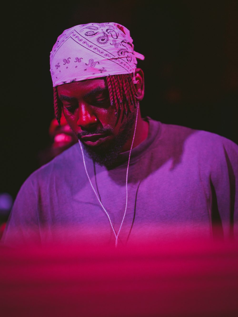 DJ Papi in a paisley bandana under pink light